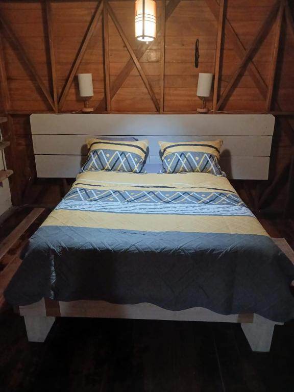 The Double Room from the foot of the bed, a pendant light overhead and a lamp on each side.