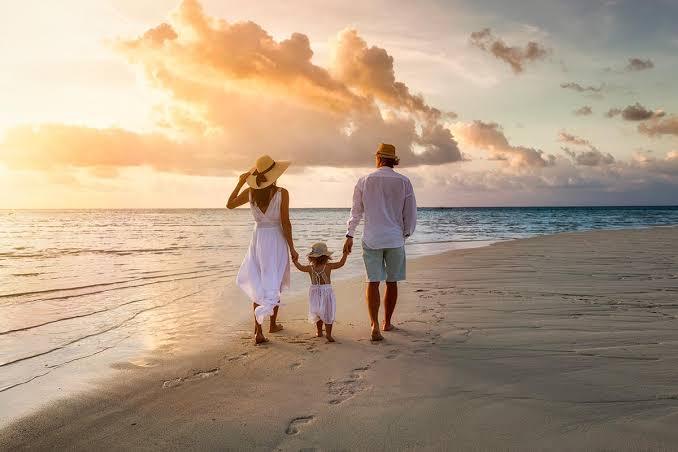 A family walking together along the sand at sunset.
