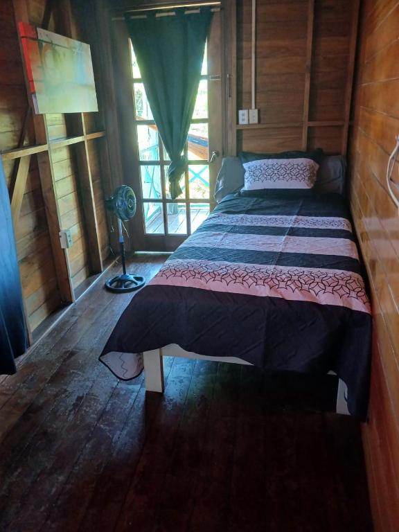 The second bedroom of the suite: a single bed beside a window and a door onto the deck, with a fan and shuttered doors.