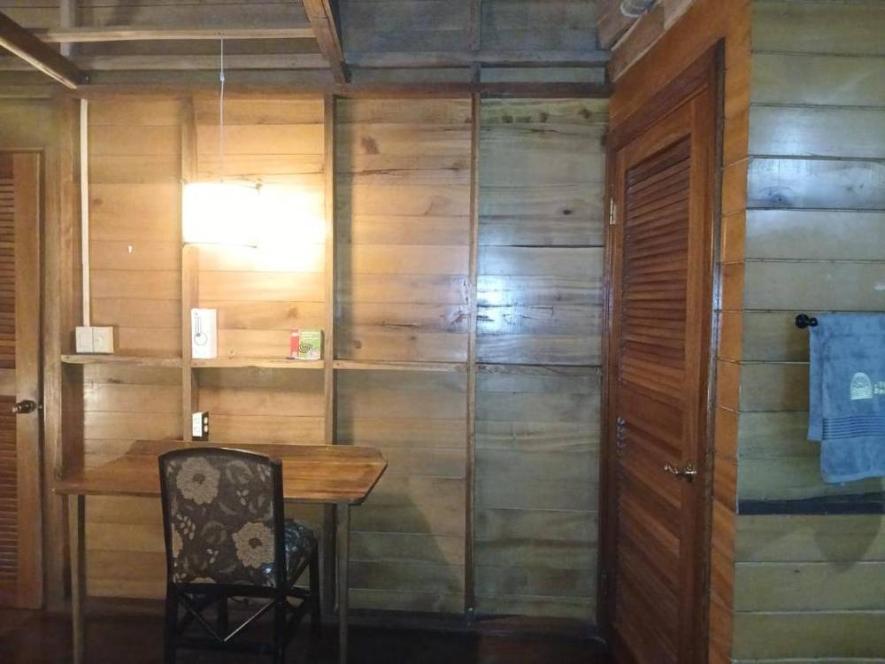 The seating corner of the Superior Double: a writing desk and chair against the timber wall, a pendant light above and a wardrobe alongside.