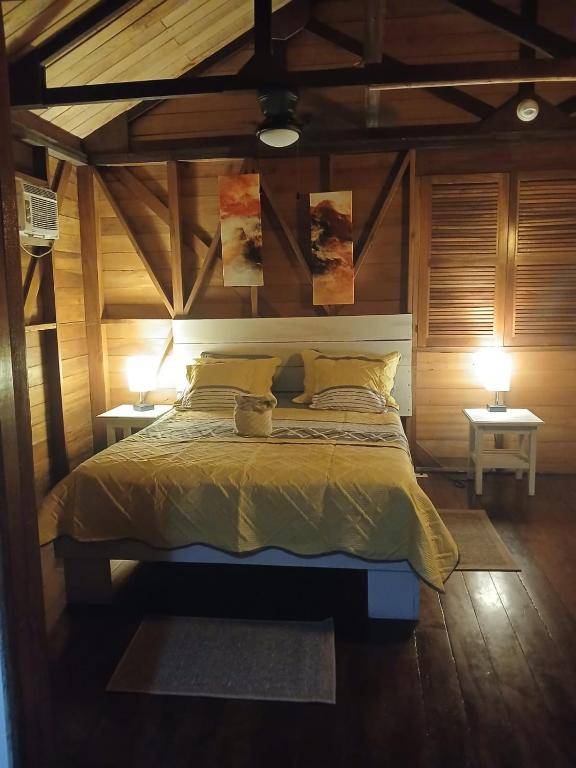 The Superior Double seen from the doorway — the bed against the timber wall, a ceiling fan overhead, air conditioning and a wide plank floor.