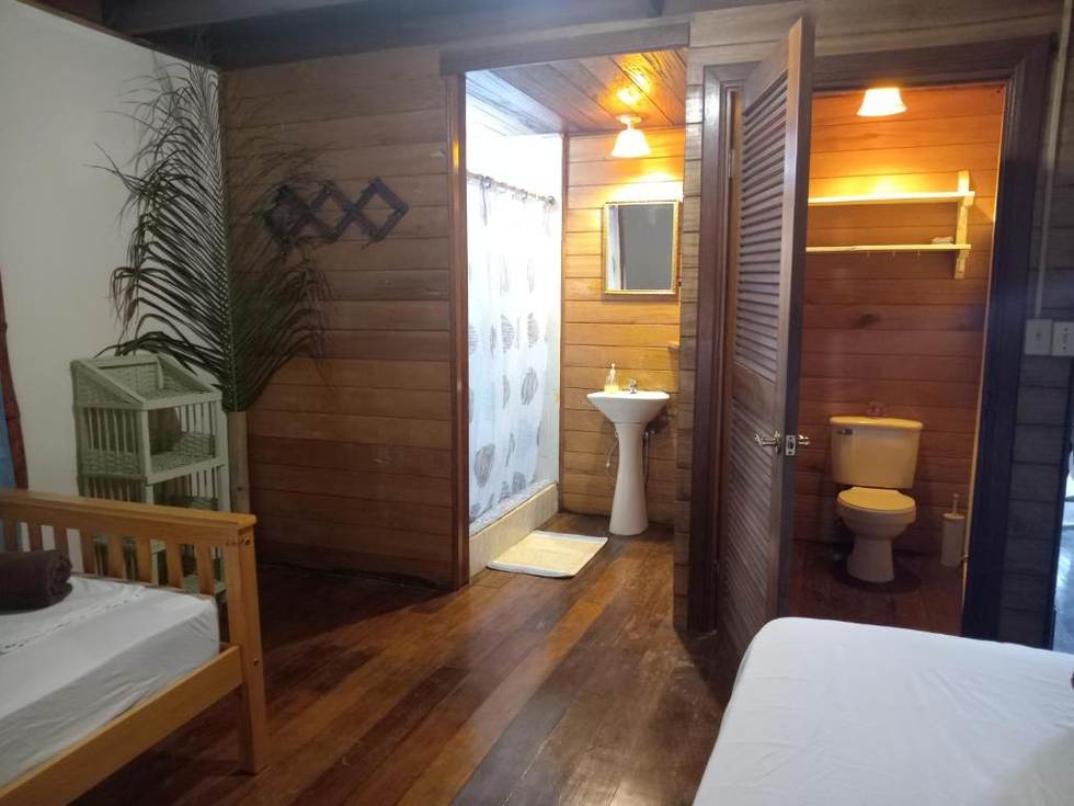 The Twin Room's shower room: a curtained shower and basin in timber, with a separate toilet through a louvred door.